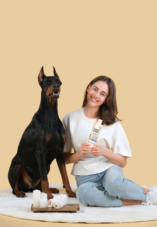 Owner with Doberman holding Lumi-noble Fragrance Free Sensitive Pet Shampoo bottle